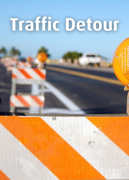 Road Construction barriers with a blue sky background Text: Traffic Detour