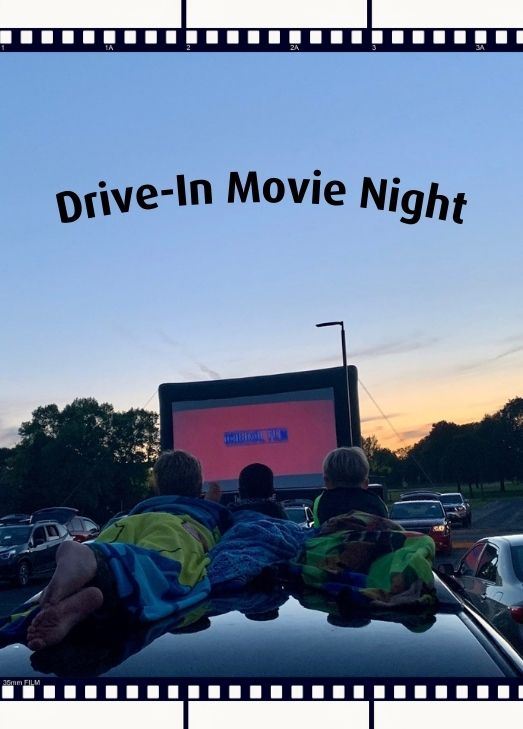 Kids laying down watching a movie on a large screen with the sunset behind Text: Drive-In Movie