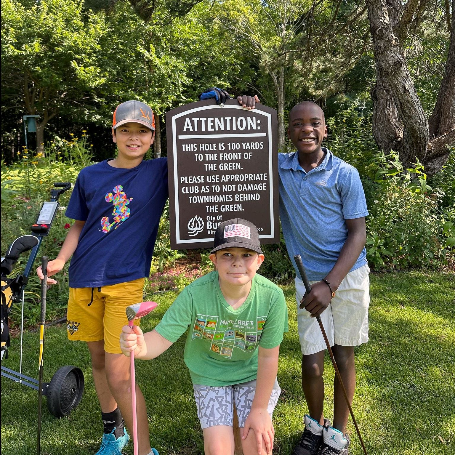 Young golfers in front of sign