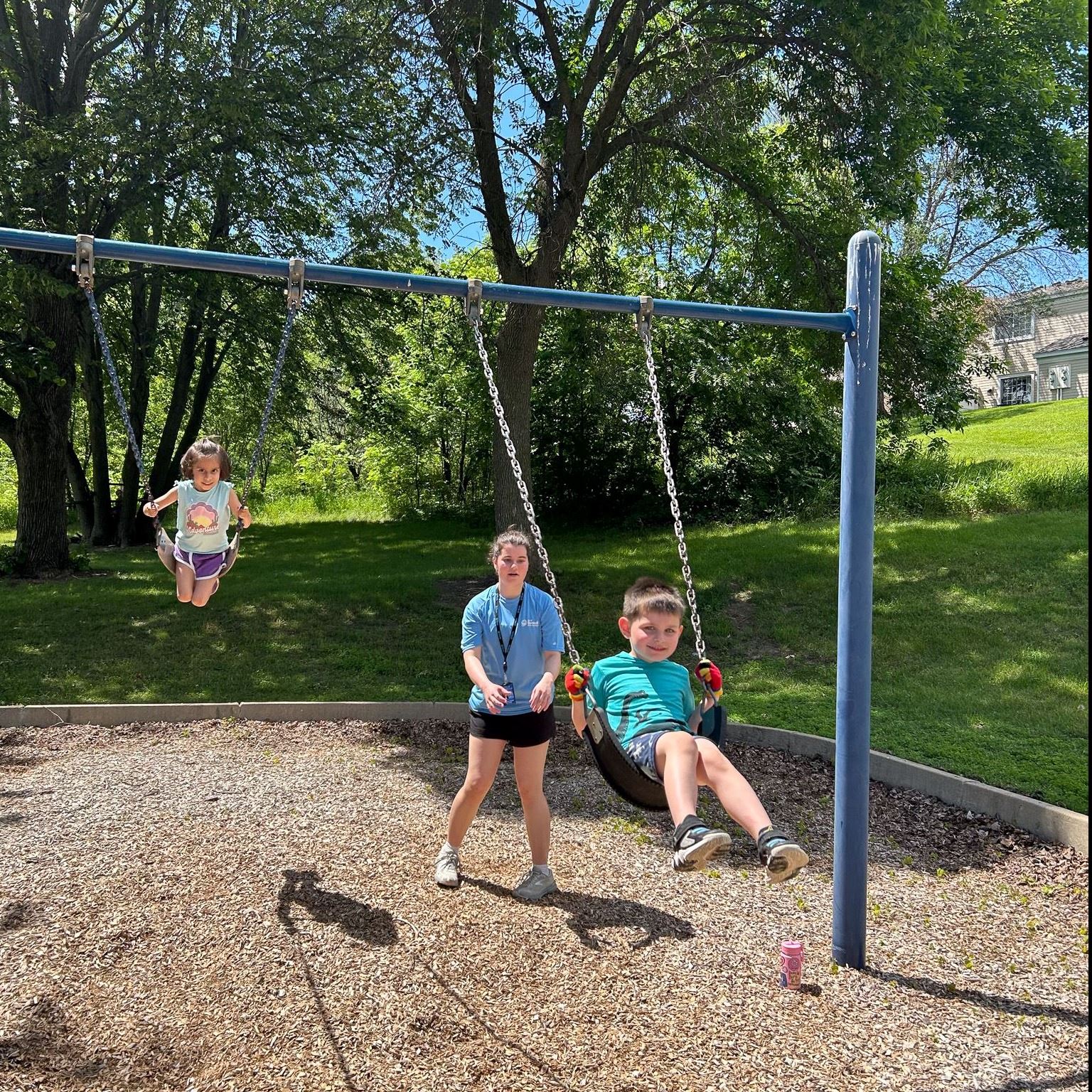 Recreation leader pushing kids on the swings