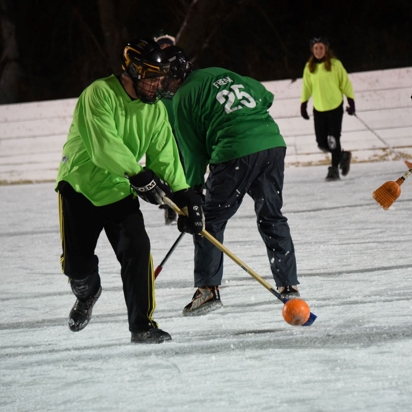 broomball players in green jerseys passing the ball