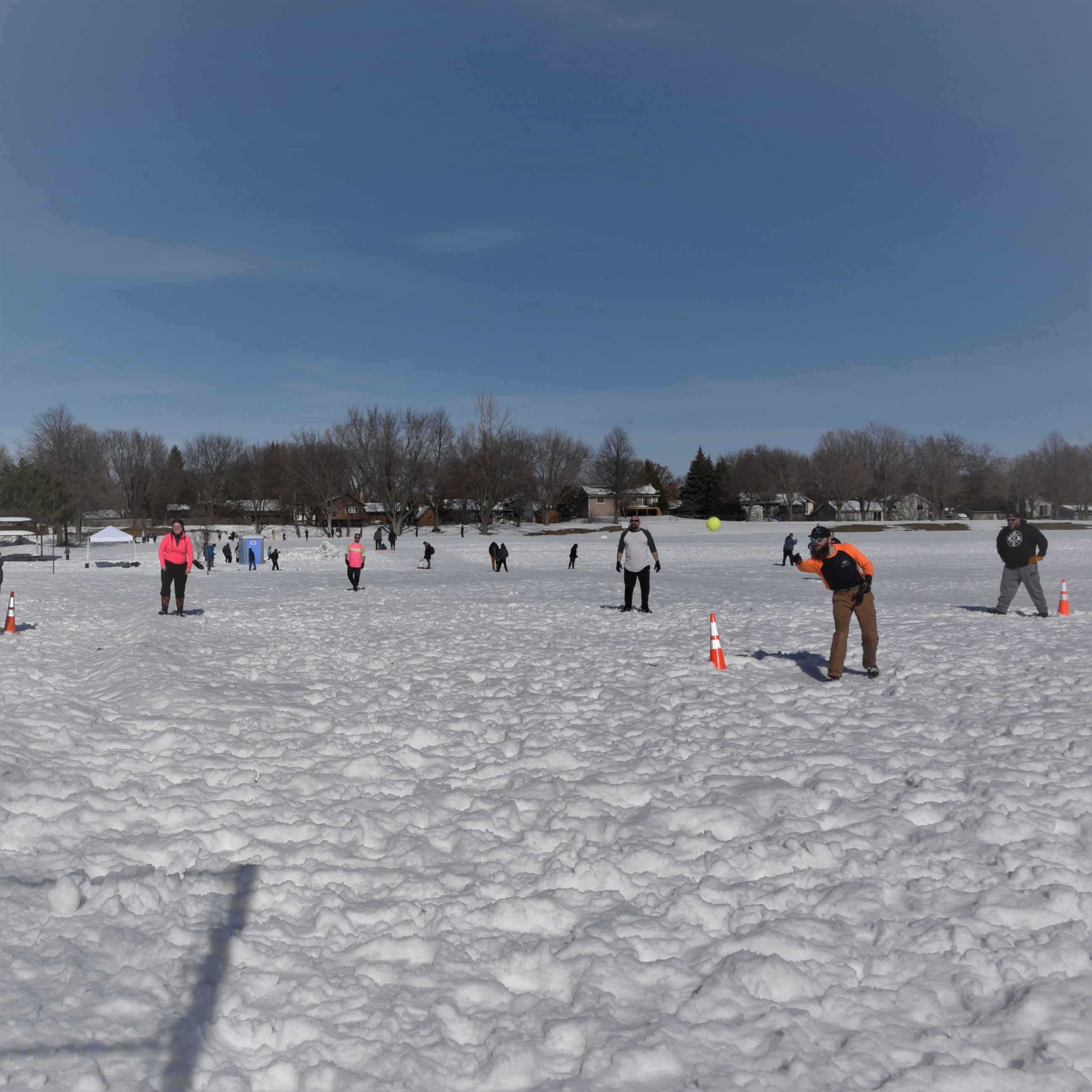 Pitcher throwing ball in winter softball game with players in the background